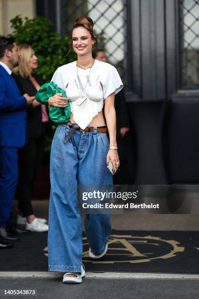 Dree Hemingway wears a gold large chain necklace, a silver long chain pendant necklace, a white bra swimwear, a white asymmetric cropped t-shirt, a...