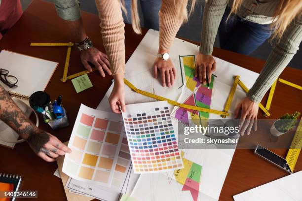 vista anterior de los diseñadores que trabajan en los planos en la oficina. - diseñador gráfico fotografías e imágenes de stock