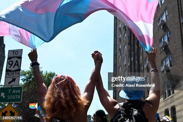 Two trans people hold hands while marching under a trans pride flag in the New York City Pride Parade on June 26, 2022 in New York City. Planned...