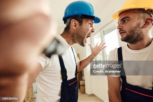 frustrated worker screaming at his colleague during home renovation process. - agressie stock pictures, royalty-free photos & images