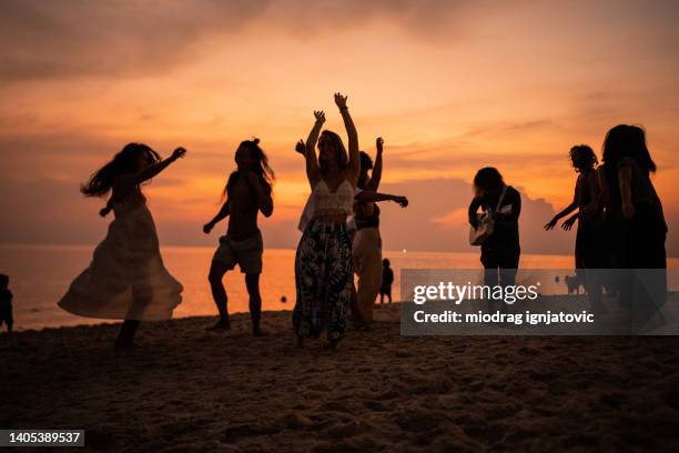 multiracial male and female friends dancing on the beach during sunset - beach music stock pictures, royalty-free photos & images