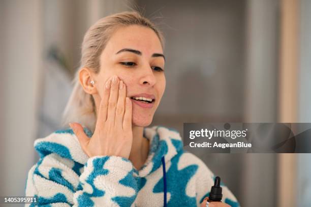 young woman applying against serum - face oil stock pictures, royalty-free photos & images