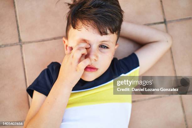 cute tired boy lying on tiled terrace - kid rubbing eyes stock pictures, royalty-free photos & images