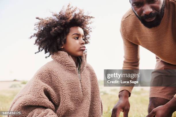 young boy in fathers jumper, being helped by his father during a road trip to the beach with his family. - fleece stoff stock-fotos und bilder