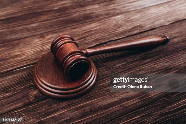 brown judge's gavel over stand against wooden background. - verurteilung stock-fotos und bilder