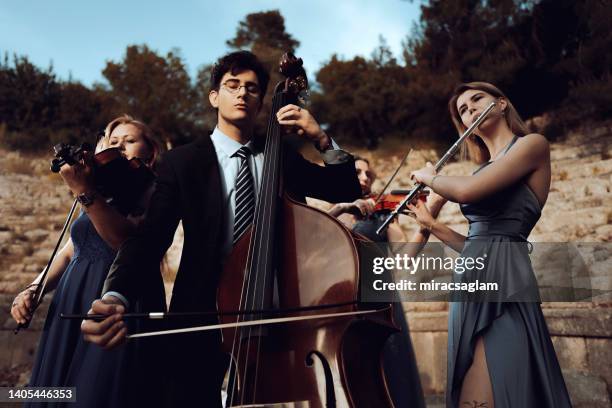 three musicians in blue dress and one musician in black suit in ancient theater. - orquestra imagens e fotografias de stock
