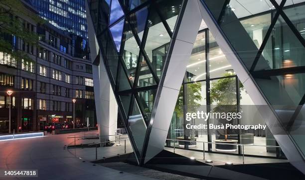 view of ground level of the gherkin office highrise building in the city of london, at twilight. london, england - swiss re tower stock pictures, royalty-free photos & images