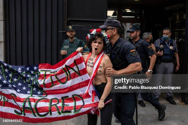 Activist with body paint reading 'Roe has fallen but we have not' holds an American flag reading 'Abortion is sacred' is disrupted by police officers...