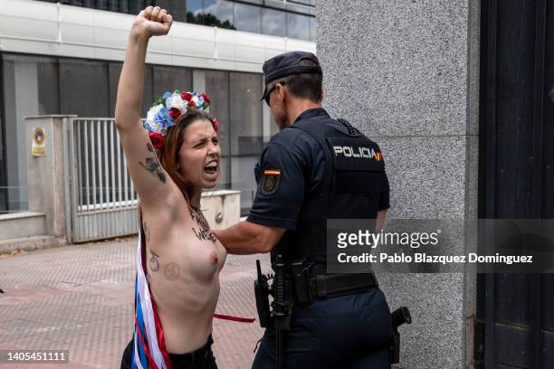 Activist with body paint reading 'Roe has fallen but we have not' protests as a police officer leads her away outside the US Embassy against the US...