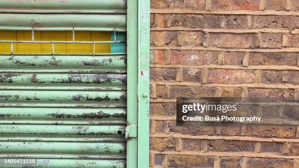 closeup of brick wall and rusty roll up metal gate - iron roll stockfoto's en -beelden