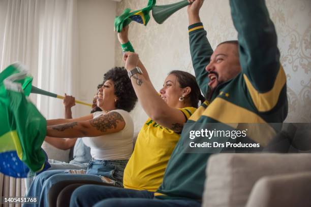 happy friends watching football game and celebrating goal - a brazil supporter stockfoto's en -beelden