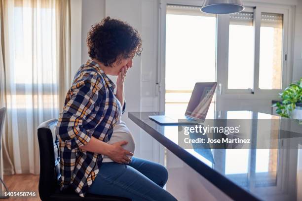 nauseous pregnant woman working at home with laptop - krankenstand stock-fotos und bilder