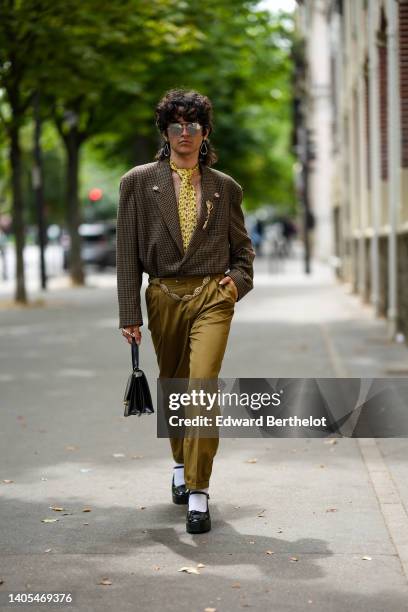 Guest wears sunglasses, silver earrings, a yellow with embroidered multicolored ballon print pattern silk tie, a brown and black houndstooth print...