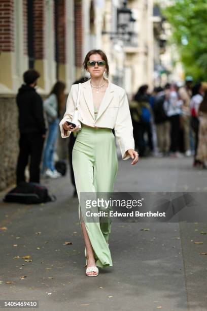 Guest wears green sunglasses, gold earrings, a white pearls necklace, a gold chain pendant necklace, a pale green laces waist V-neck top, matching...