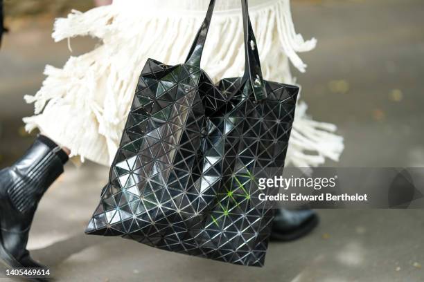 Guest wears a white ruffled long dress, a black shiny leather Bao Bao handbag from Issey Miyake, outside the Kenzo show, during Paris Fashion Week -...