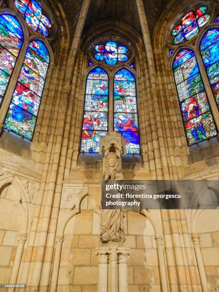 Gothic sculpture of a smiling Virgin in the Santa Maria de la Regla de Leon Cathedral and vibrant stained glass windows, Leon, Spain