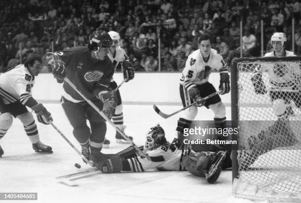 Black Hawks' goalie Murray Bannerman trips up Red Wings' Ted Nolan while trying to make an unsuccessful save in the first period of the game. Looking...