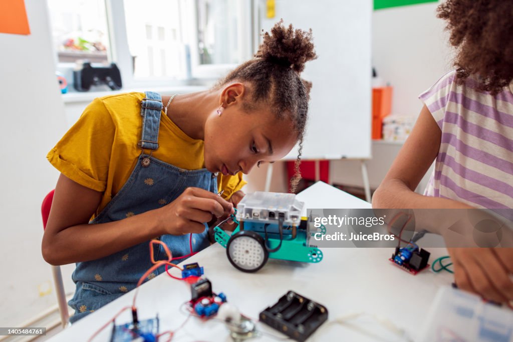 Focused girl on STEM class, making robots