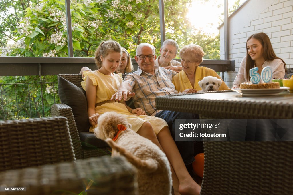 Senior couple cuddling with their offspring and dogs while celebrating 50th anniversary