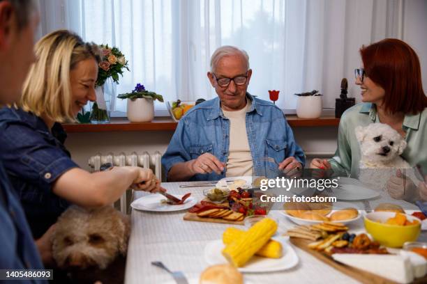 familia sentada en la mesa del comedor, disfrutando de deliciosa comida y unión - dog thanksgiving fotografías e imágenes de stock