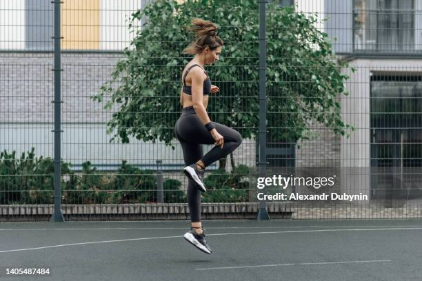 a fit woman goes in for sports on the sports ground. sport woman jump. female jogging workout.workout outdoor in summer. - athlete bulges stock pictures, royalty-free photos & images