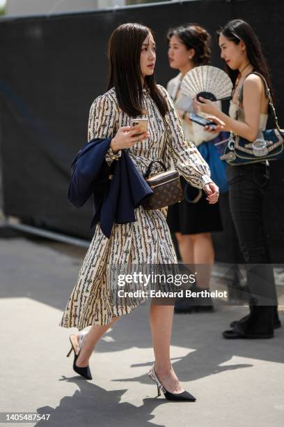 Guest wears a beige with black and gold print pattern puffy long sleeves asymmetric midi skirt, a navy blue blazer jacket, a brown LV monogram print...