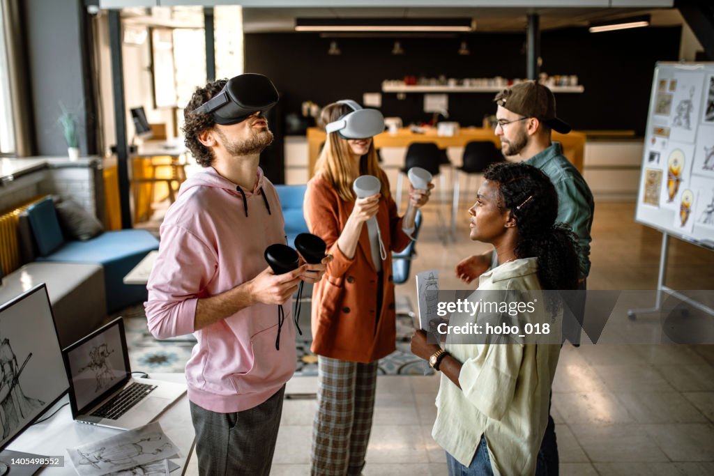 Groupe d’étudiants universitaires au bureau utilisant des casques de simulateur VR, s’amusant