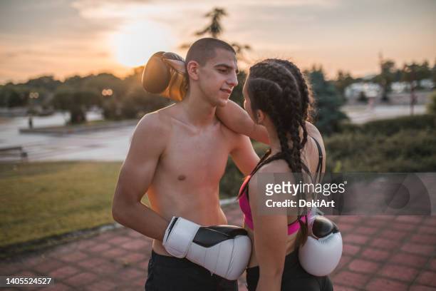 two young kickboxers in love embracing in the park - kickboxing gloves stock pictures, royalty-free photos & images