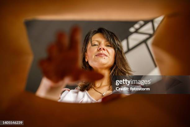 geschäftsfrau lächelt in die kamera, während sie ihre hand in einer braunen papiertüte ausstreckt - tragetasche oder tragebeutel stock-fotos und bilder