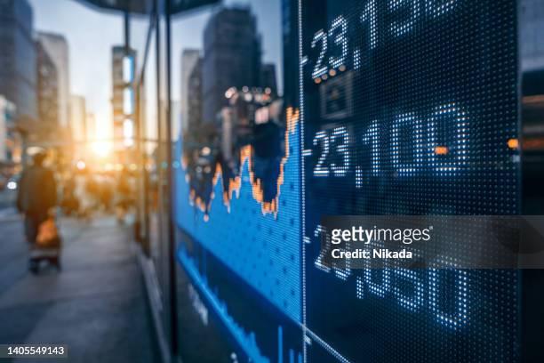 display of stock market quotes with city scene reflect on glass - news ticker imagens e fotografias de stock