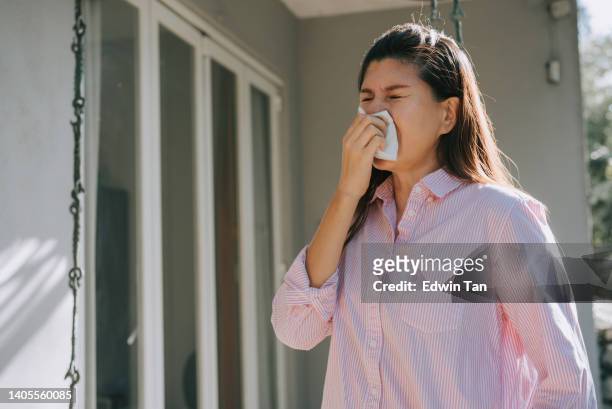 asian chinese woman sneezing outside home beside window - covering nose stock pictures, royalty-free photos & images