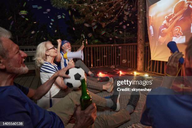 verfolgen sie ein erfolgreiches fußballspiel durch die projektionsfläche auf einer terrasse bei nacht! - weltmeisterschaft stock-fotos und bilder