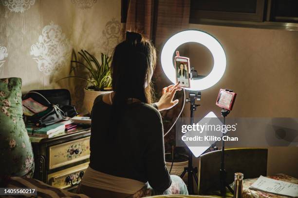 asian female influencer filming content using phone in a bedroom - webcam photo photos et images de collection