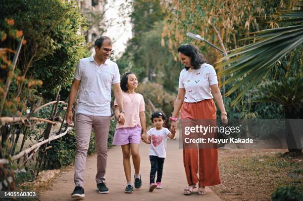 family with two daughters walking together in the garden - daily life in india photos et images de collection