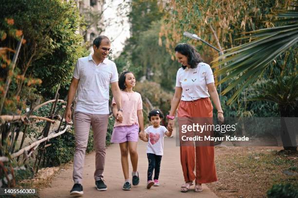 family with two daughters walking together in the garden - family bonding stock pictures, royalty-free photos & images