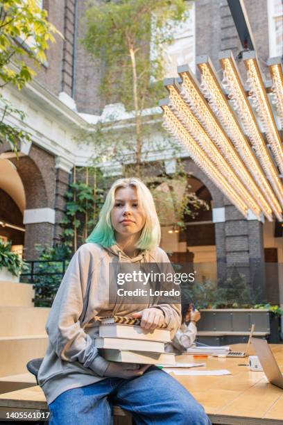 beautiful teenage female student studying in a public library - student reading book stockfoto's en -beelden