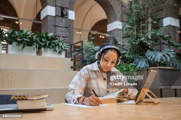 beautiful black teenage female student studying in a public library - linguistics 個照片及圖片檔