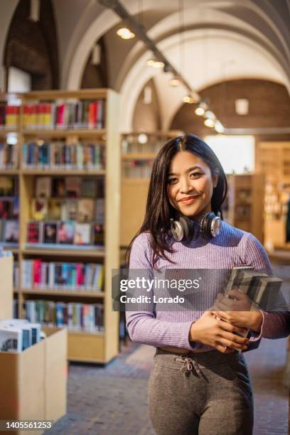 beautiful ethnic adult student studying in a public library - student reading book stockfoto's en -beelden