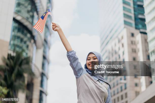 young malay woman celebrating malaysia hari merdeka - holding flag stock pictures, royalty-free photos & images