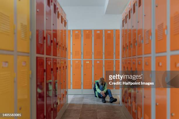 sad boy sitting in the floor in locker room. - locker room wall stock pictures, royalty-free photos & images