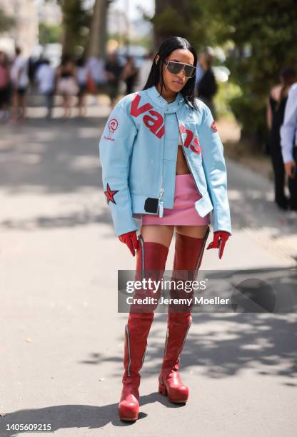 Guest seen wearing pink mirrored sunglasses, a light blue logo biker leather jacket from VANS, a white bra top, a pink leather mini short skirt, red...