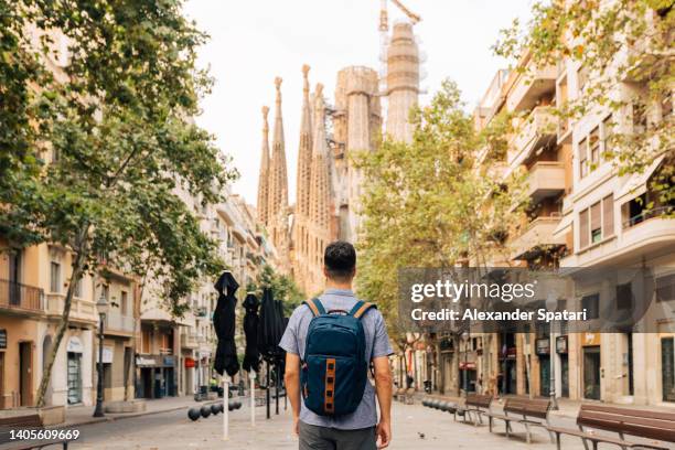 rear view of a young man with backpack looking at sagrada familia, barcelona, spain - espanha - fotografias e filmes do acervo