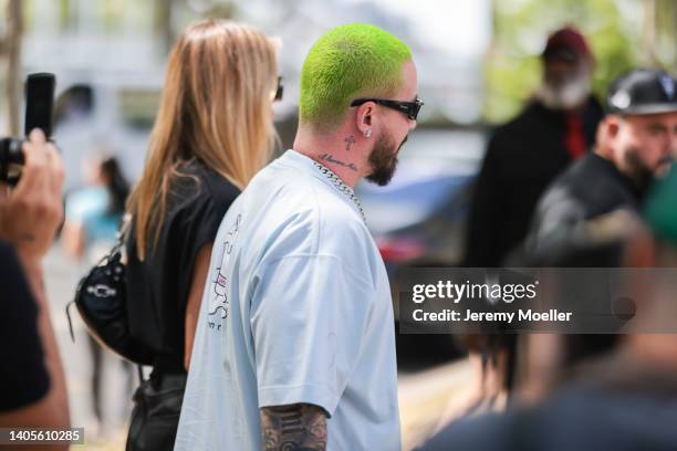 Balvin seen wearing black sunglasses from Prada, diamond earrings, a silver diamond cuban link chain necklace and a white t-shirt, outside the Rick...