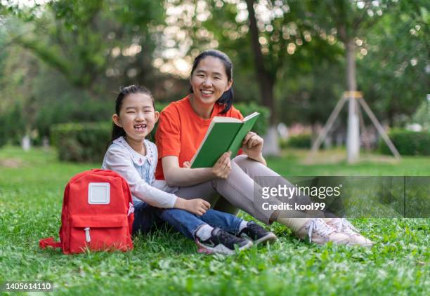 little girl and mother reading book - portrait of school children and female teacher in field stock pictures, royalty-free photos & images
