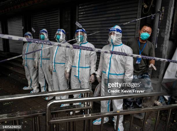 Health workers dressed in protective clothing wait to be sprayed with disinfectant after finishing their work in an area where some residents are in...