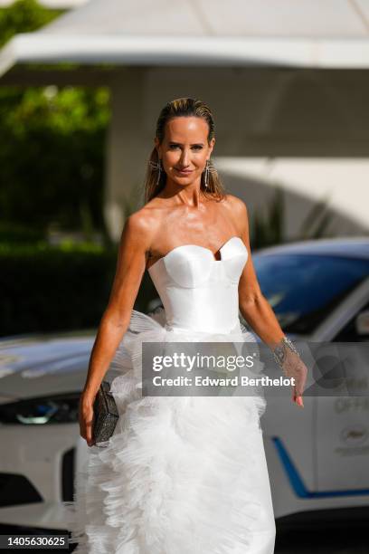 Lady Victoria Hervey wears a silver and diamonds dragonfly pendant earrings, a white shoulder-off / heart neck / ruffled tulle long dress, a silver...