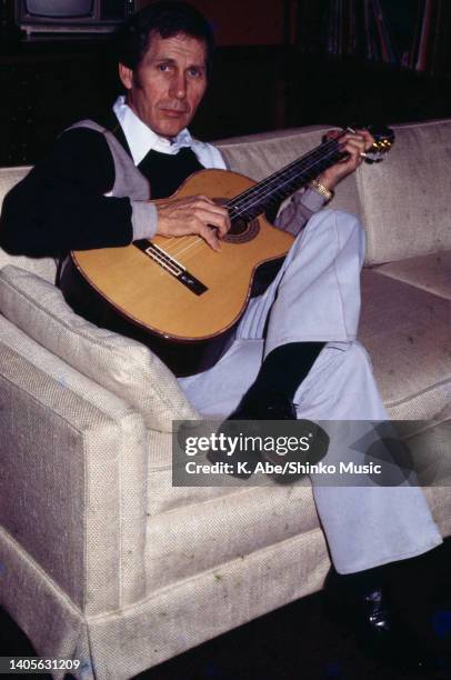 Chet Atkins plays the guitar on a sofa, RCA, Nashville, USA, 18 January 1978.