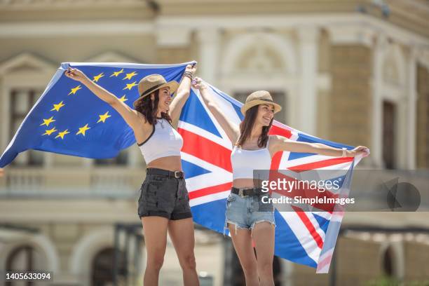 young tourists with european union and uk flags somewhere on the streets of london - eu referendum stock pictures, royalty-free photos & images