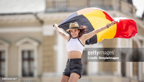 belgian flag in the hands of a young tourist in summer clothes - national holiday stock pictures, royalty-free photos & images