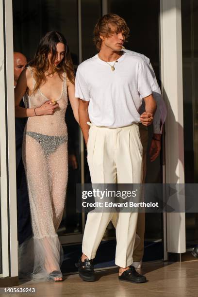 Guest wears a transparent embroidered rhinestones V-neck / long dress, black open toe-cap pumps heels shoes, Jordan Barrett wears gold chain pendant...